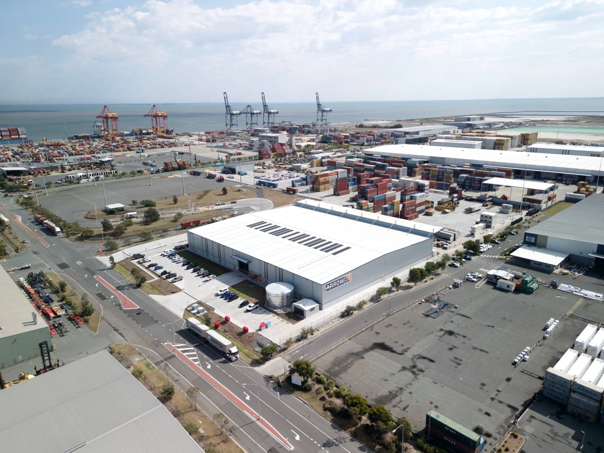 Aerial drone shot of an Arrow Transport warehouse beside a container terminal
